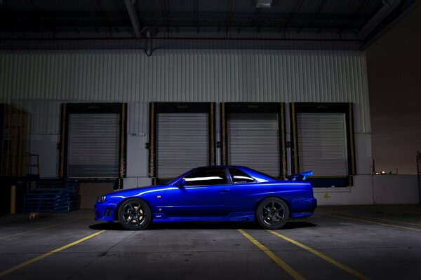 Автомобиль Nissan r34 синего цвета стоит в тёмное время на улице